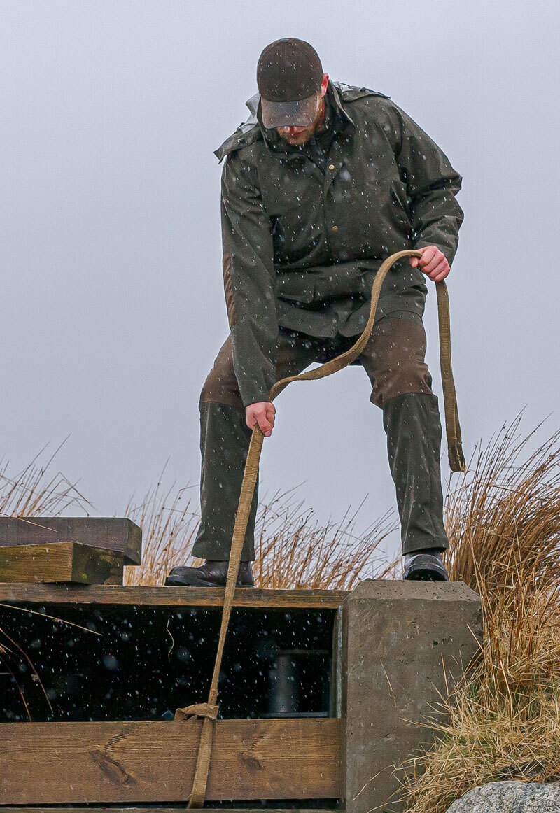Man gardening wearing Hoggs of Fife Green King waterproof jacket in wet conditions