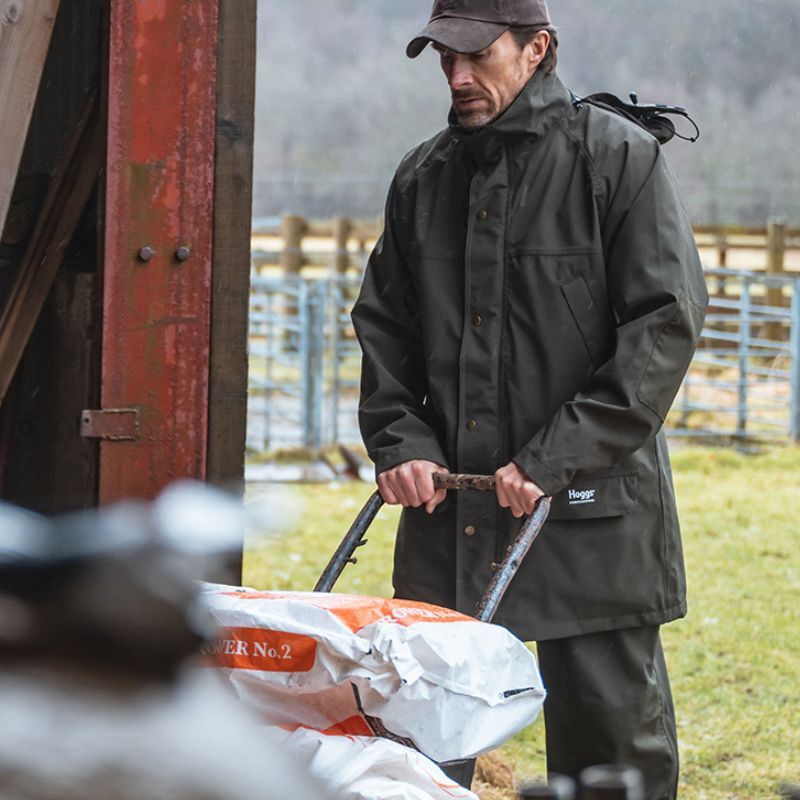 Man pushing garden trolley wearing waterproof gardening jacket in wet conditions