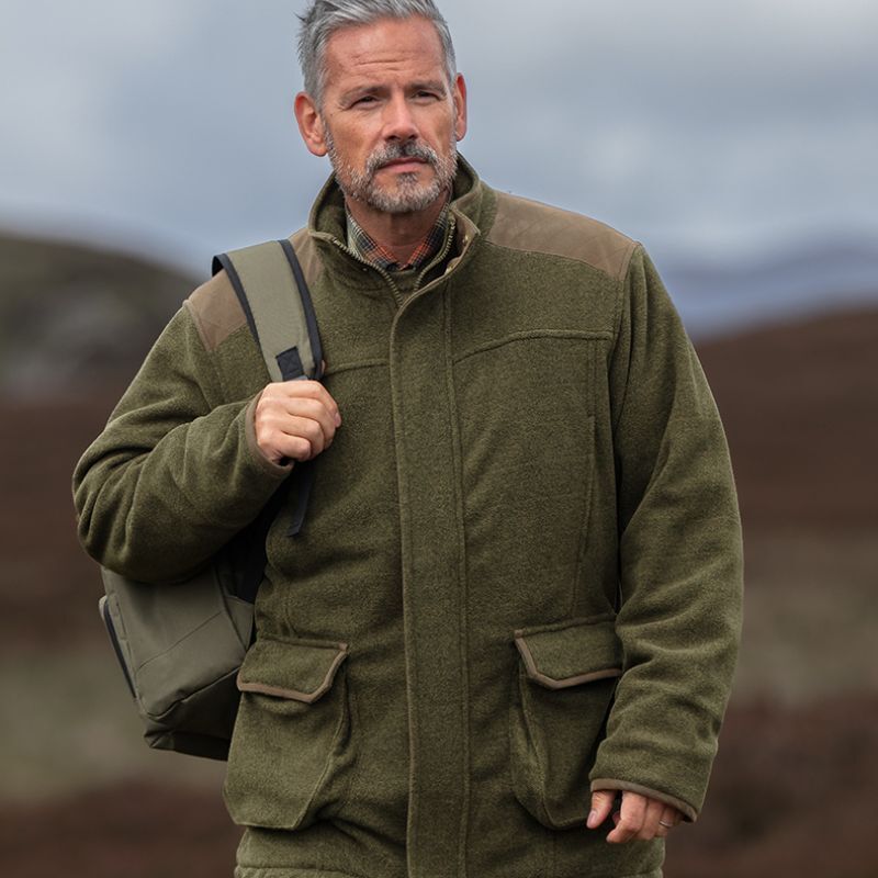 Man wearing insulated winter dog walking coat on cold hillside walk